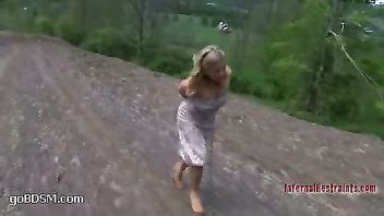 Luscious blonde restrained with an iron brace outdoors